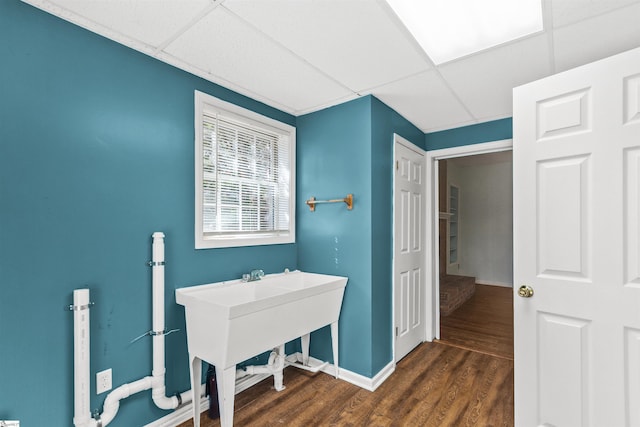 interior space with dark wood finished floors, baseboards, and a drop ceiling