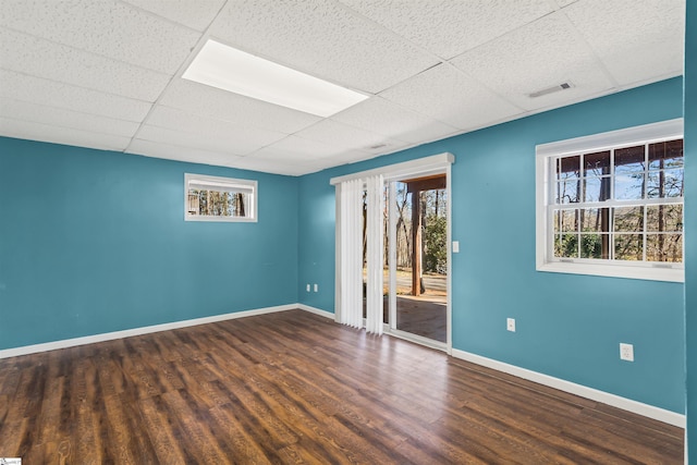 unfurnished room with a wealth of natural light, a paneled ceiling, and wood finished floors
