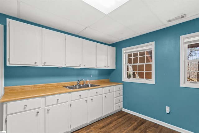kitchen featuring visible vents, a sink, light countertops, white cabinetry, and dark wood-type flooring