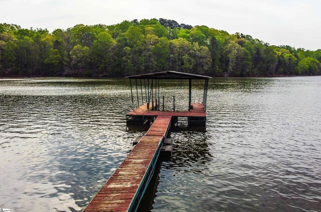 view of dock featuring a water view and a forest view