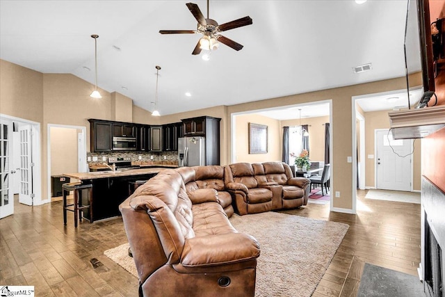 living room with baseboards, visible vents, hardwood / wood-style floors, ceiling fan, and high vaulted ceiling