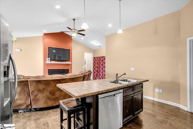 kitchen featuring a ceiling fan, wood finished floors, a sink, lofted ceiling, and stainless steel appliances