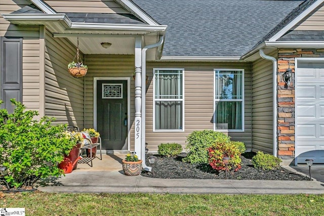 entrance to property with a shingled roof, a garage, and stone siding
