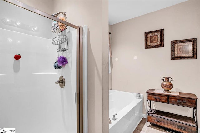 full bath featuring baseboards, a stall shower, and a garden tub