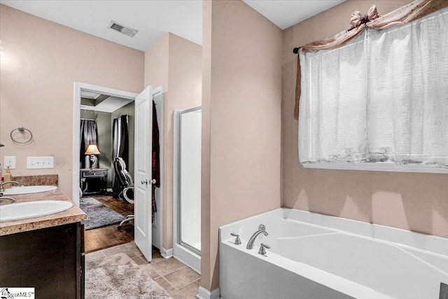 full bath featuring visible vents, a bath, a sink, a shower stall, and double vanity