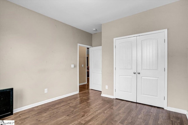 unfurnished bedroom with wood finished floors, baseboards, and a closet