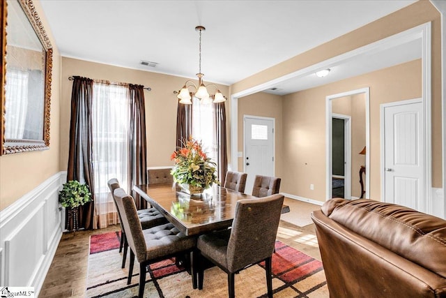 dining room featuring a notable chandelier, wainscoting, and visible vents