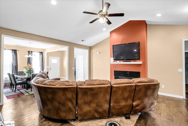 living area with visible vents, dark wood-type flooring, ceiling fan, a large fireplace, and lofted ceiling