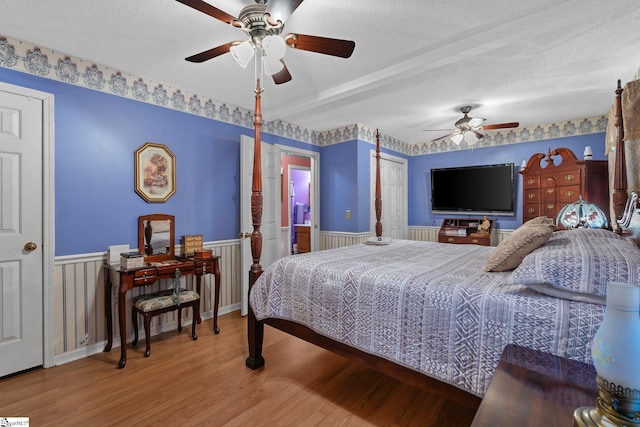 407 Rotterdam Rd, Easley, SC 29640 - bedroom with connected bathroom, a textured ceiling, a ceiling fan, a wainscoted wall, and wood finished floors