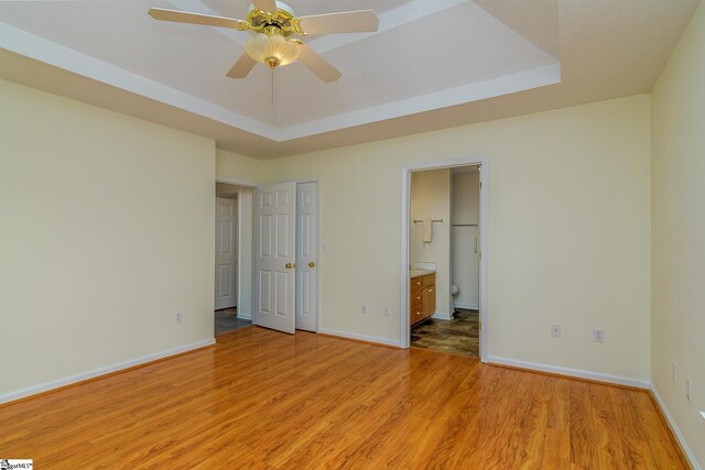 15 Red Cedar Ct, Simpsonville, SC 29681 - unfurnished bedroom with a tray ceiling, light wood-type flooring, baseboards, and connected bathroom