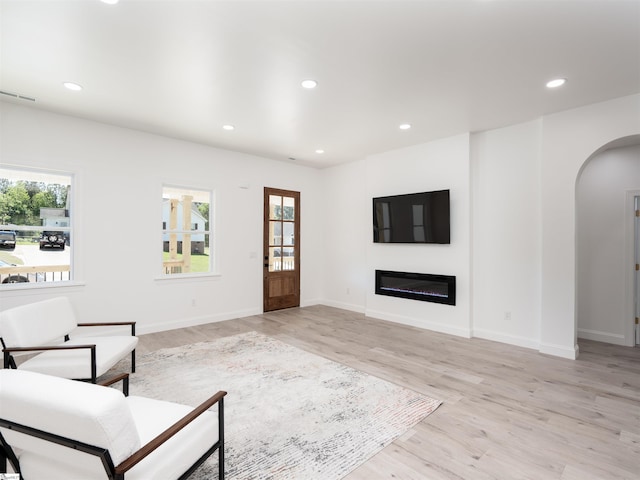 242 Queensbury Way, Spartanburg, SC 29302 - unfurnished living room with recessed lighting, arched walkways, a glass covered fireplace, and light wood-style floors
