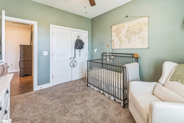 carpeted bedroom featuring a closet, baseboards, and a nursery area