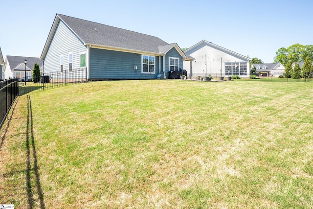 rear view of house with fence private yard and a lawn