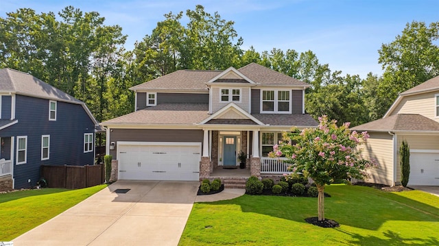 craftsman house with roof with shingles, driveway, an attached garage, a front yard, and covered porch