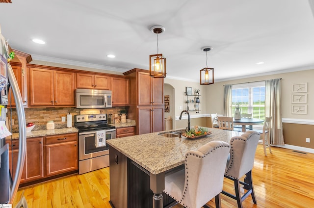 kitchen featuring stainless steel appliances, a sink, crown molding, a kitchen breakfast bar, and backsplash