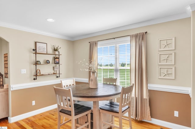 dining space with ornamental molding, light wood finished floors, baseboards, arched walkways, and recessed lighting