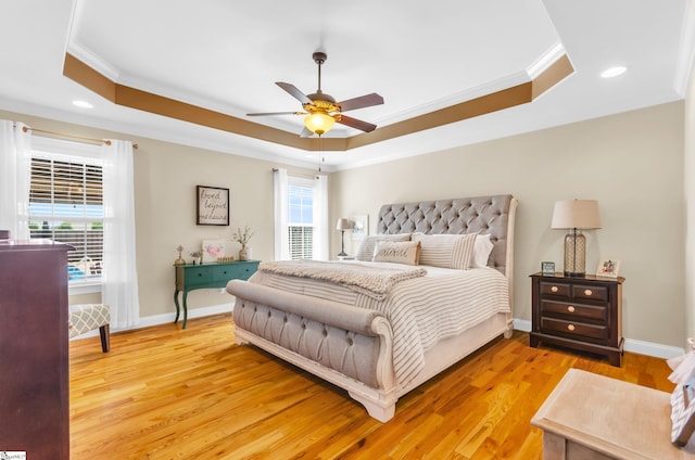bedroom with ornamental molding, a raised ceiling, recessed lighting, light wood finished floors, and baseboards