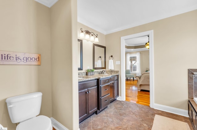 bathroom featuring crown molding, toilet, double vanity, a ceiling fan, and baseboards