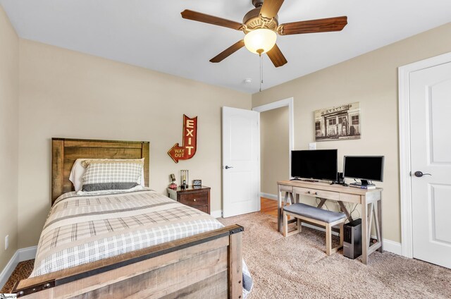 bedroom with light carpet, baseboards, a desk, and ceiling fan