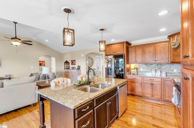 kitchen with a sink, stainless steel appliances, arched walkways, ceiling fan, and open floor plan