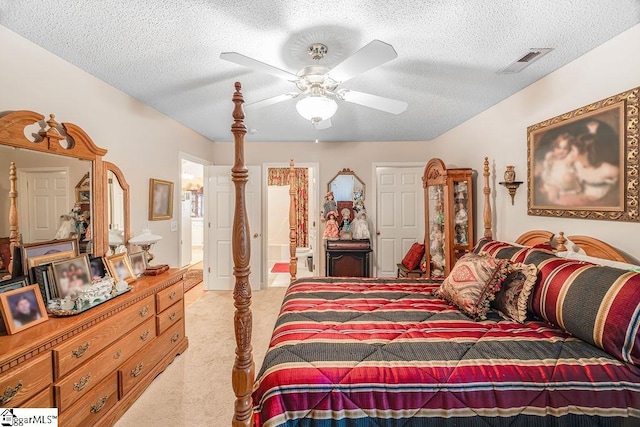 bedroom featuring a textured ceiling, light colored carpet, ensuite bath, and visible vents