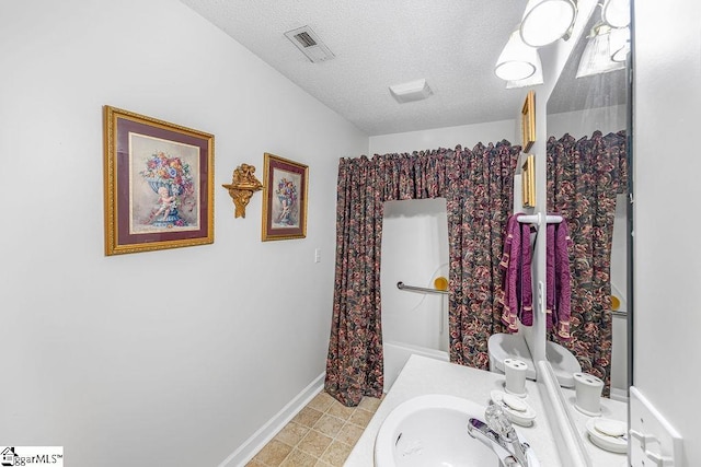 bathroom featuring visible vents, baseboards, vanity, and a textured ceiling