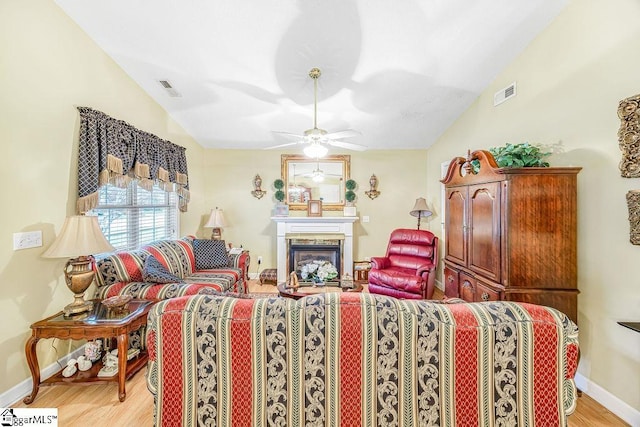 living area featuring visible vents, baseboards, ceiling fan, light wood finished floors, and lofted ceiling