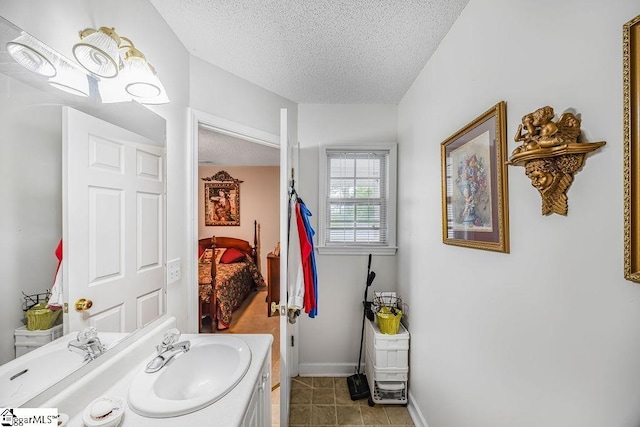 bathroom featuring tile patterned flooring, baseboards, vanity, and a textured ceiling