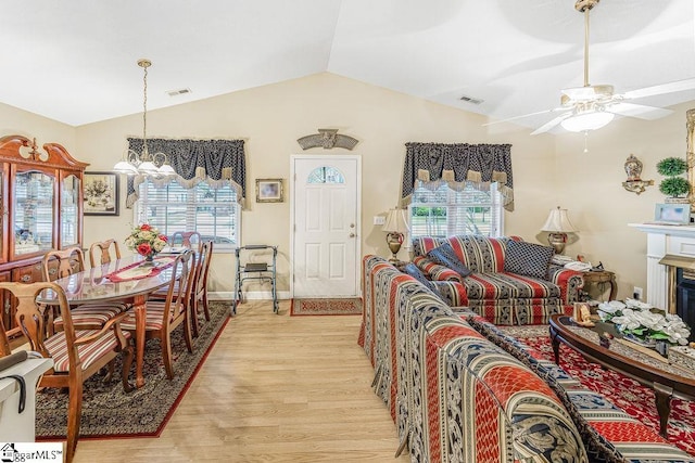 living room featuring light wood-style floors, visible vents, ceiling fan with notable chandelier, and lofted ceiling