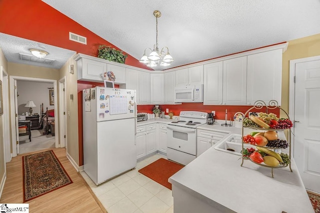 kitchen with vaulted ceiling, an inviting chandelier, white appliances, a textured ceiling, and visible vents
