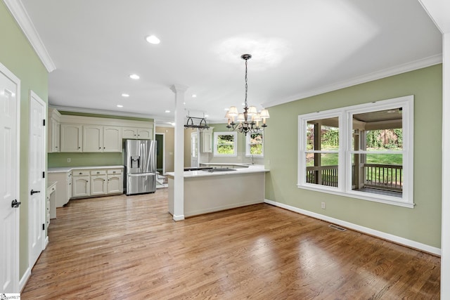 kitchen featuring crown molding, visible vents, stainless steel fridge, and a peninsula