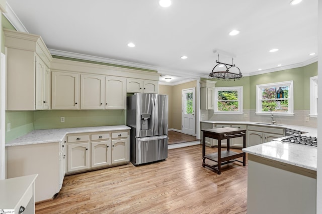 kitchen featuring stainless steel fridge with ice dispenser, light wood-type flooring, ornamental molding, decorative backsplash, and a sink