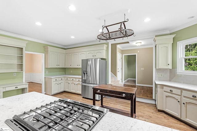 kitchen with crown molding, light stone countertops, light wood finished floors, and stainless steel appliances