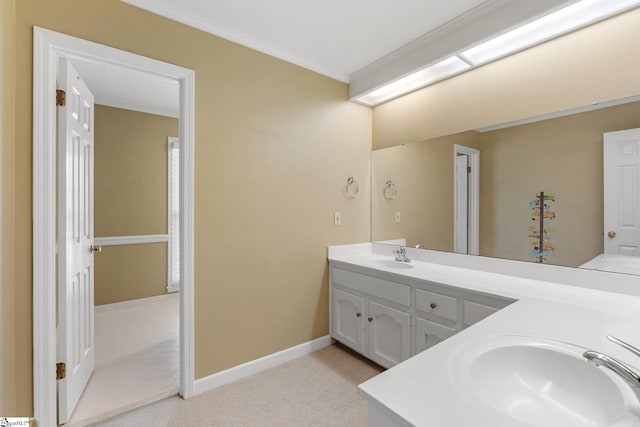 bathroom with a sink, baseboards, double vanity, and crown molding