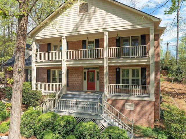 view of front of home featuring brick siding, covered porch, and stairs