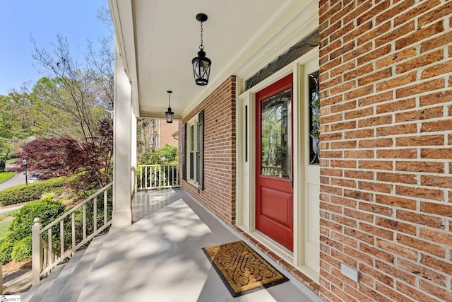 view of exterior entry with a porch and brick siding