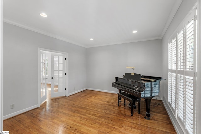living area with wood finished floors, baseboards, and ornamental molding