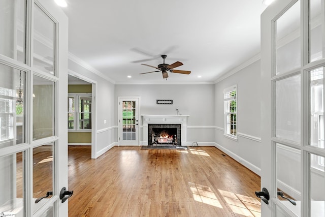 unfurnished living room featuring baseboards, light wood-style floors, a lit fireplace, and a ceiling fan