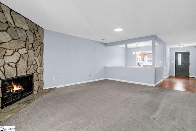 unfurnished living room featuring dark carpet, a fireplace, and baseboards