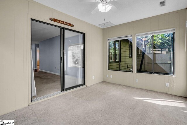 carpeted empty room with visible vents and ceiling fan