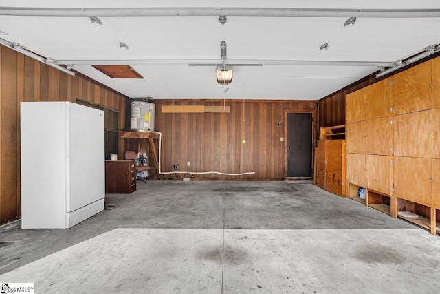 garage featuring wood walls, a garage door opener, water heater, and freestanding refrigerator