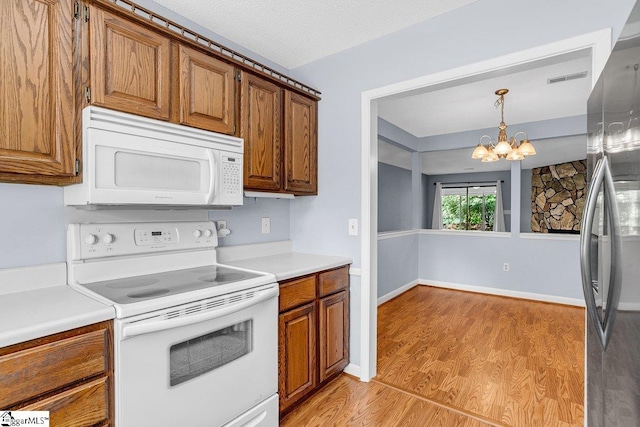 kitchen featuring white appliances, brown cabinetry, light wood-type flooring, light countertops, and a notable chandelier