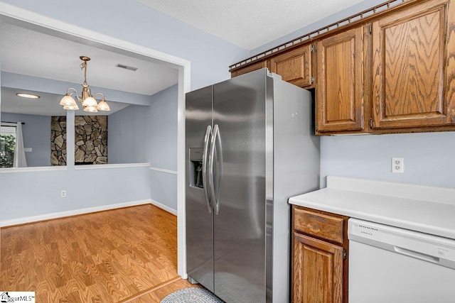 kitchen with dishwasher, brown cabinets, visible vents, and stainless steel fridge