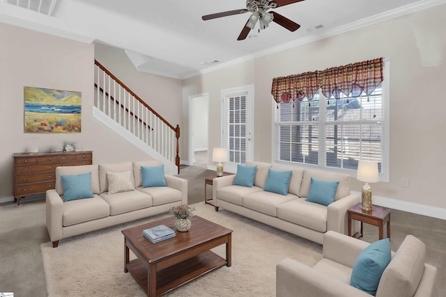 carpeted living area featuring stairway, visible vents, ornamental molding, and ceiling fan