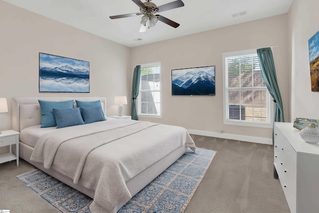 carpeted bedroom with a ceiling fan, baseboards, multiple windows, and visible vents