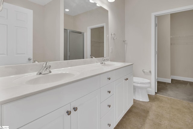 bathroom featuring a shower stall, a walk in closet, a sink, and toilet