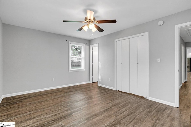 unfurnished bedroom featuring a closet, baseboards, attic access, and wood finished floors