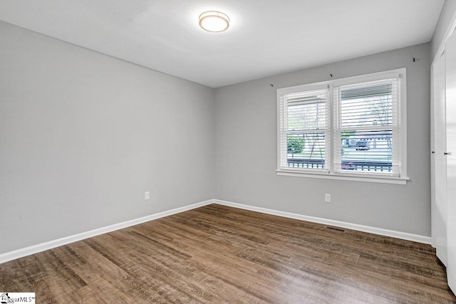 spare room featuring visible vents, baseboards, and wood finished floors