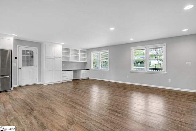 unfurnished living room featuring baseboards, dark wood finished floors, and recessed lighting