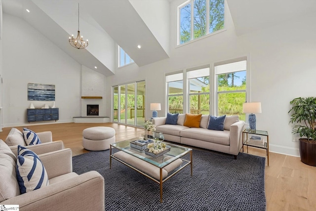 living room featuring light wood-style flooring, a high ceiling, a notable chandelier, and baseboards